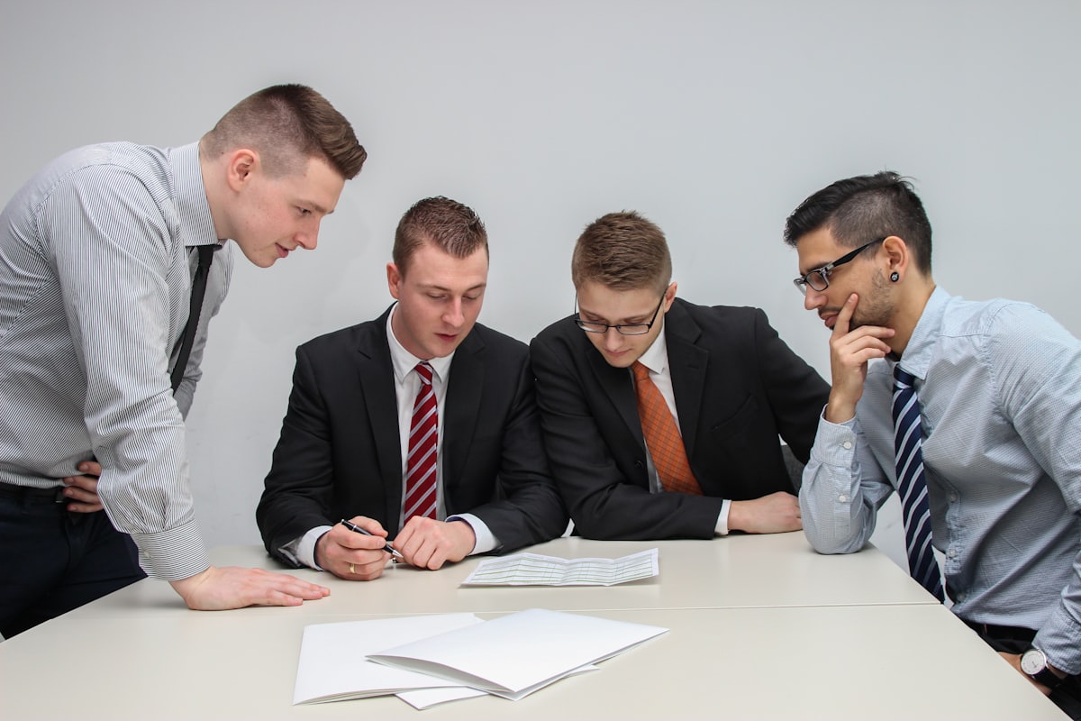 Quatre collaborateurs examinant ensemble des documents de travail.